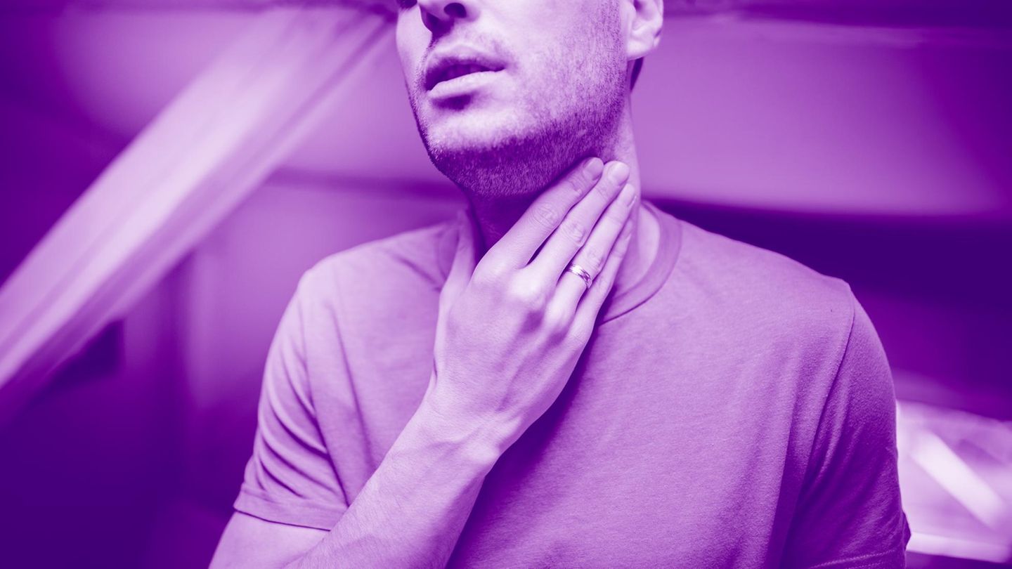 Ein Mann fasst sich an den Hals