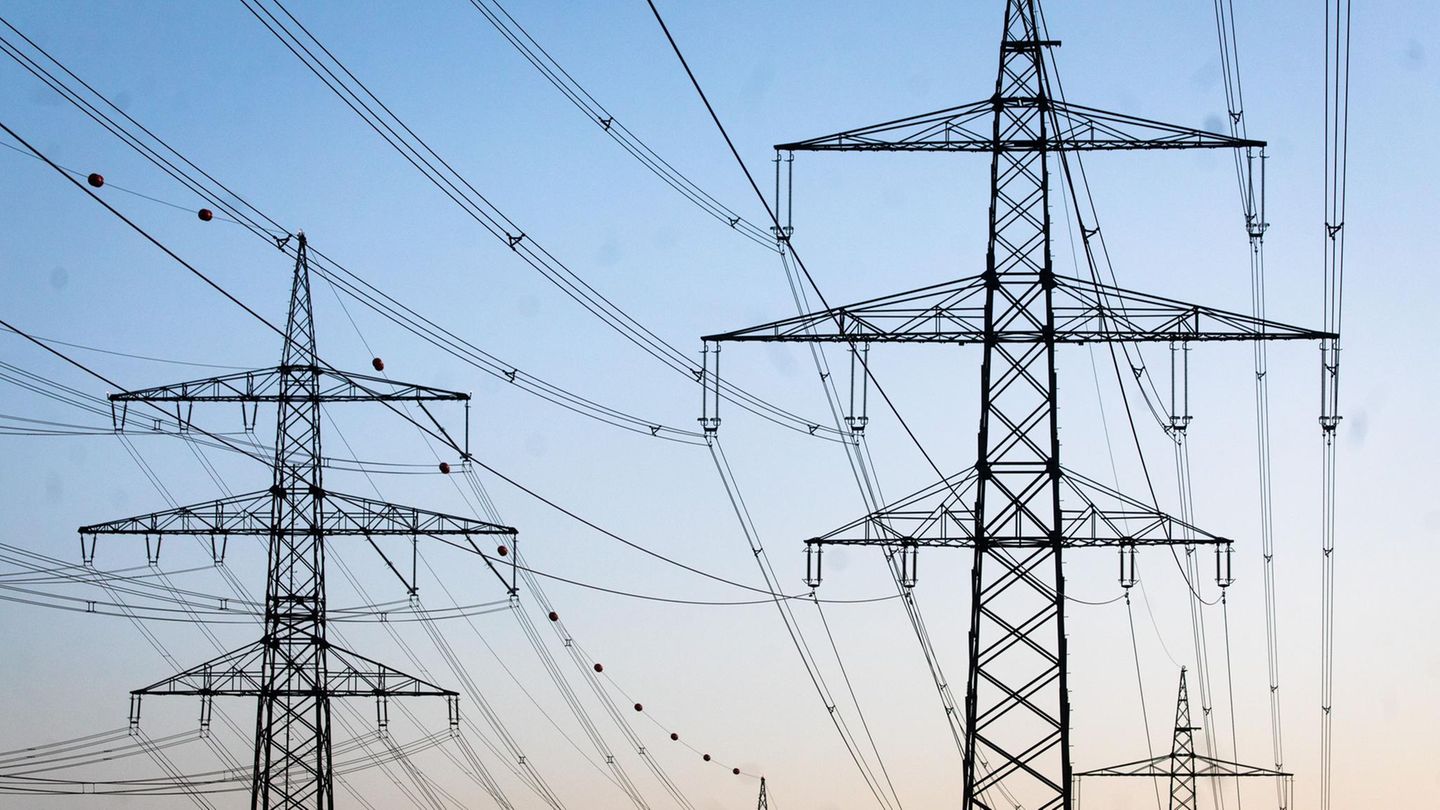 SFreileitungsmasten stehen kurz vor Sonnenaufgang auf einem Feld