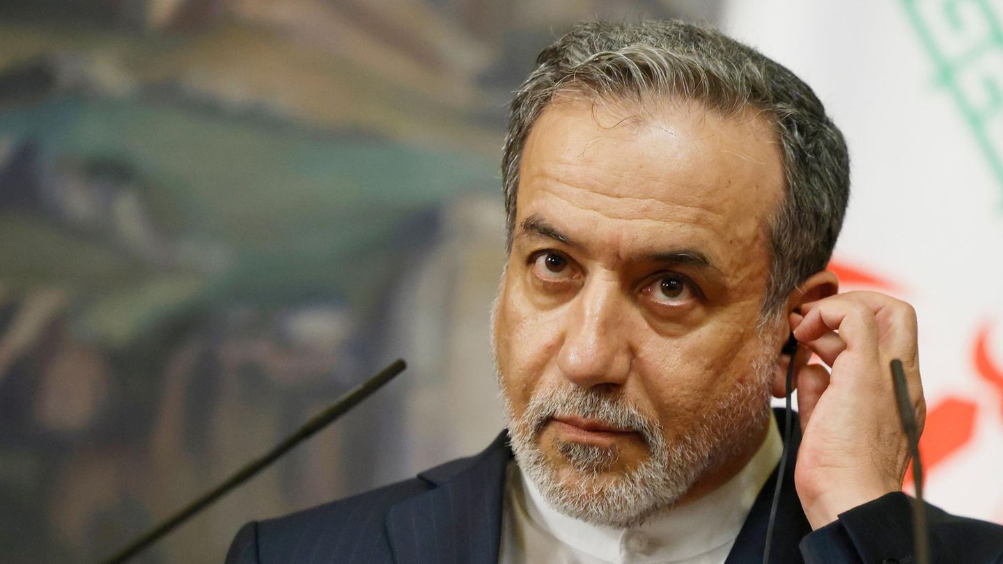 Abbas Araghtschi, Außenminister des Iran,  setzt sich einen Ohrhörer ins linke Ohr