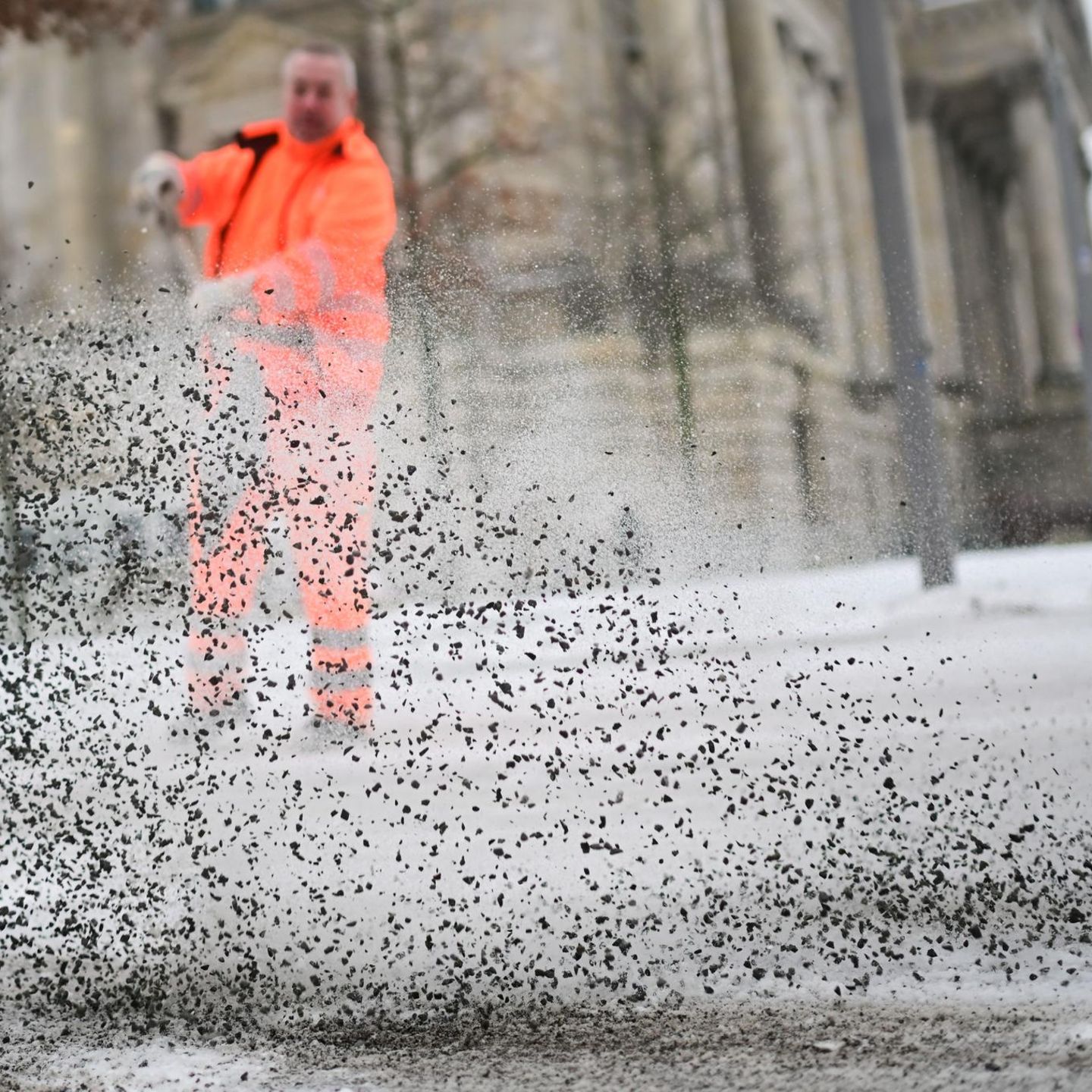 BSR-Mitarbeiter streut statt Streusalz Rollsplit auf vereiste Straße.