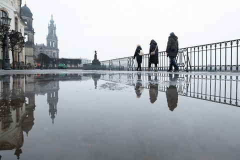 Passanten gehen auf der Brühlschen Terrasse vor der Katholischen Hofkirche in Dresden entlang. Ein regnerischer Start ins Wochen