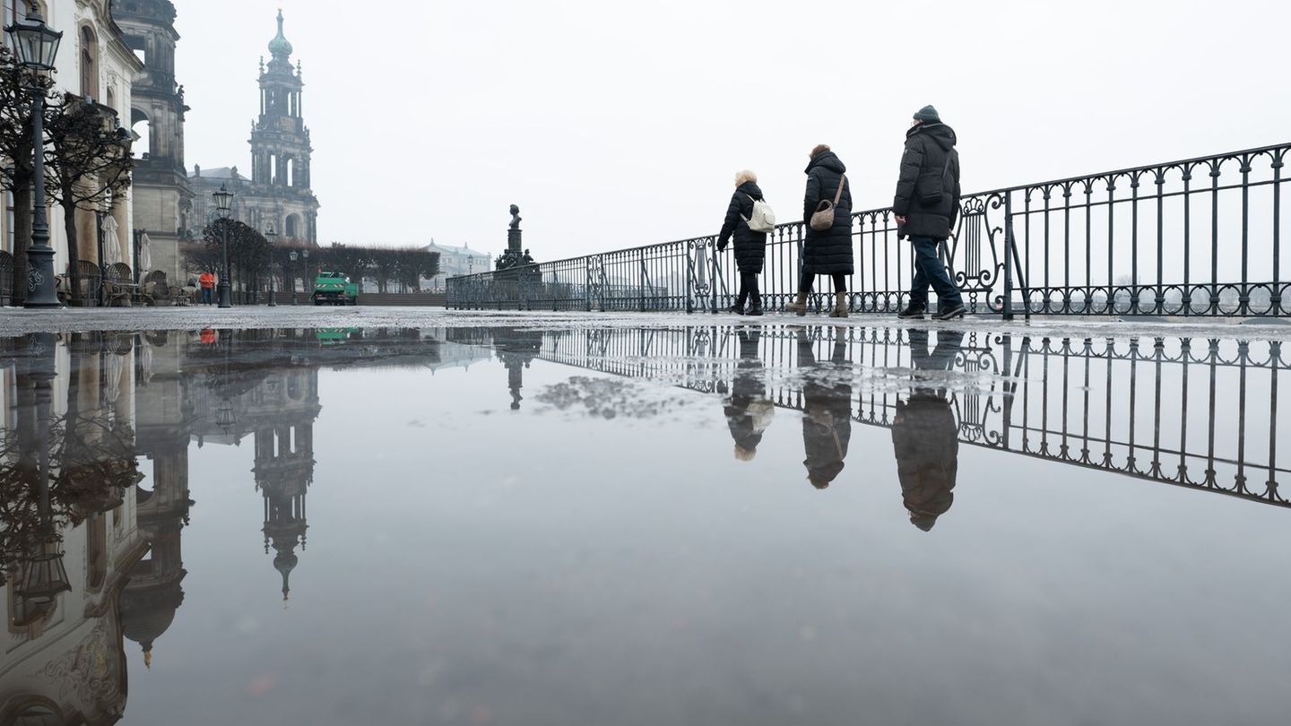 Passanten gehen auf der Brühlschen Terrasse vor der Katholischen Hofkirche in Dresden entlang. Ein regnerischer Start ins Wochen