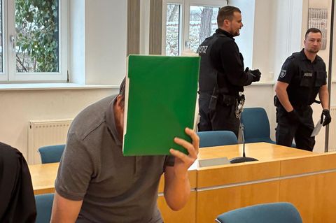 Ein Mann in einem Gerichtssaal in Erfurt verbirgt sein Gesicht hinter einer grünen Mappe