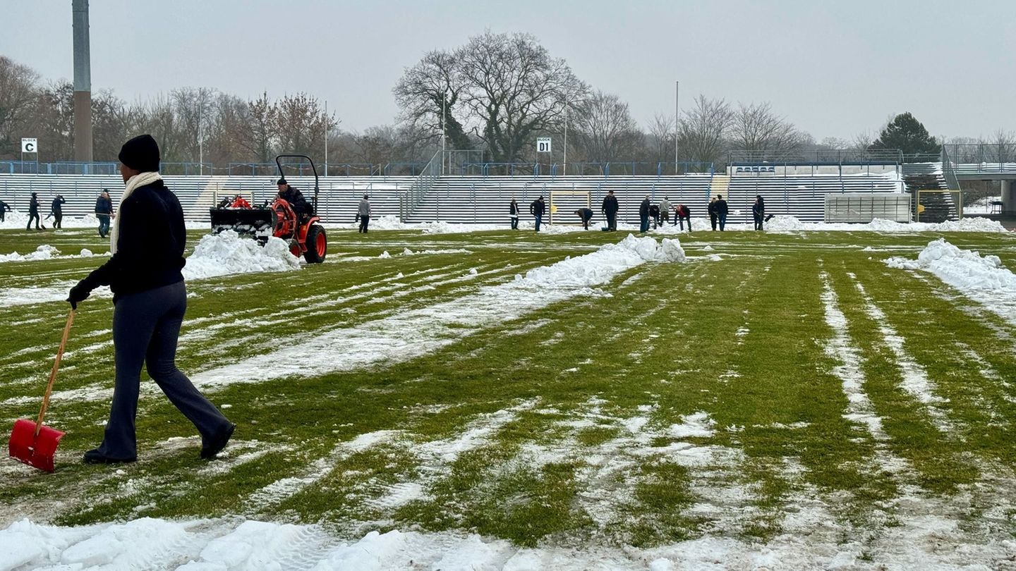Freiwillige räumen Schnee von der Spielfläche im Dessauer Paul-Greifzu-Stadion Foto: Thomas Schulz/dpa