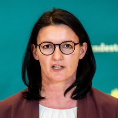 Irene Mihalic spricht vor einer grünen Wand mit dem Sonnenblumen-Logo der Grünen