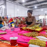 Eine Schneiderin steht vor pinken und goldenen Stoffen