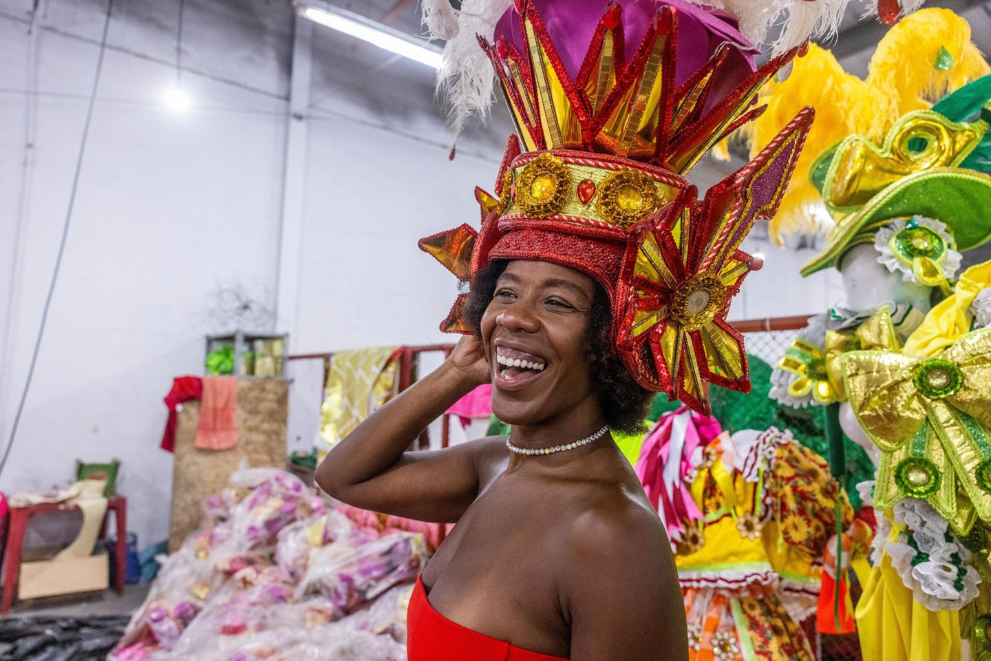 Eine Frau lacht, sie hat eine rot-goldene Kopfbedeckung auf
