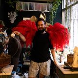 Ein Designer steht in seinem Atelier, er hat eine Federboa um