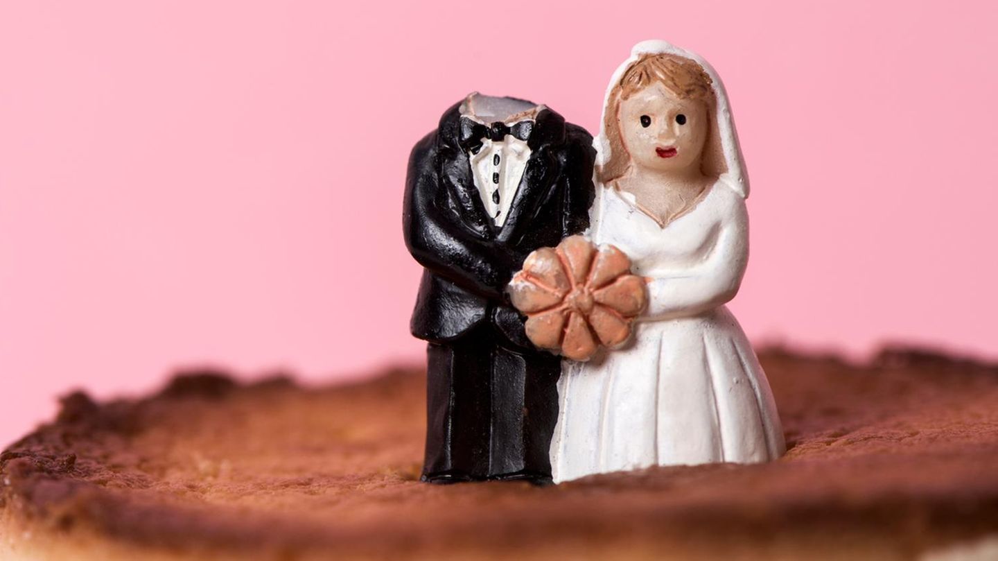 Ein Hochzeitspaar auf einer Torte, wobei der Kopf des Bräutigams fehlt