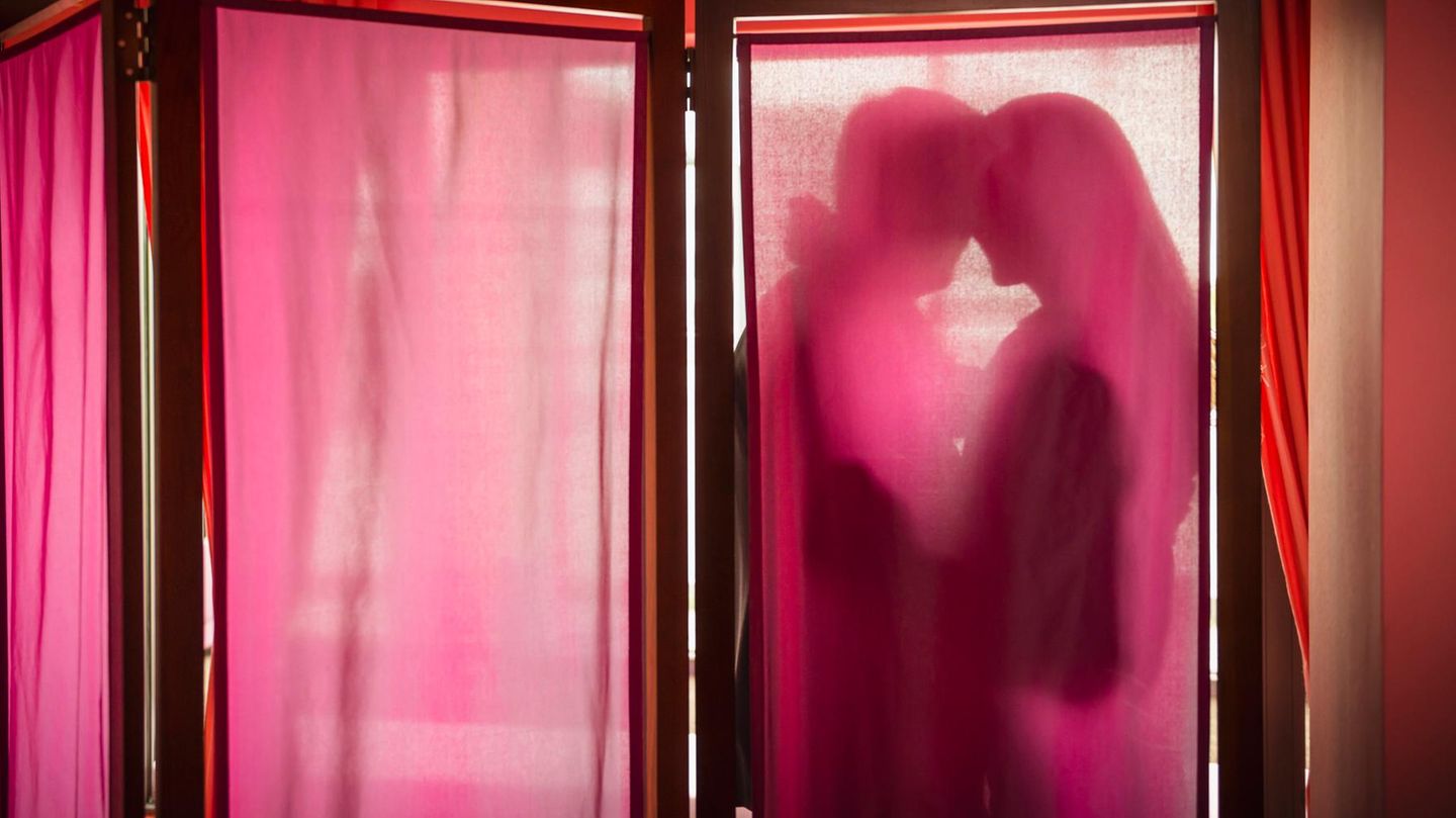 Ein Paar hinter einem Vorhang (Symbolbild Sugarbabe mit Sugardaddy)