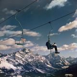 Mit Skiern auf dem Schoß sitzt eine Frau im Lift