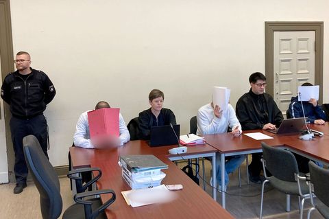 Die drei wegen versuchten Mordes angeklagten Männer verbergen ihre Gesichter vor den Kameras der Pressevertreter. Foto: Bernhard