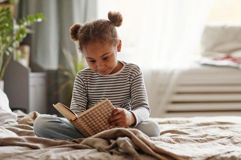 Kinder allein zu Hause lassen: Symbolbild. Mädchen im Grundschulalter liest ein Buch