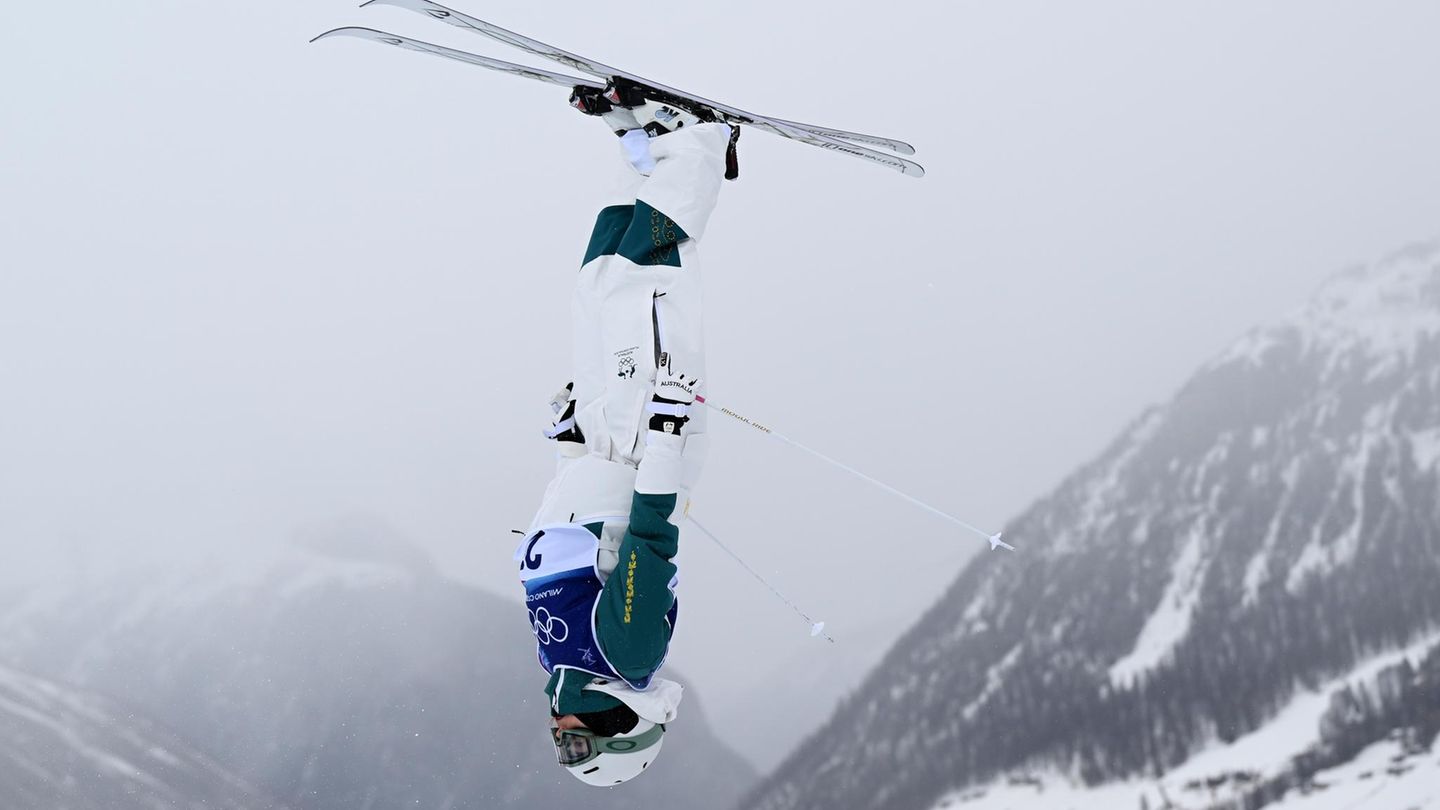 Livigno, Italien. Bei den Olympischen Winterspielen zeigt Emma Bosco aus Australien ihre beeindruckende Technik im Freestyle-Skifahren. Der graue Himmel und das verschneite Alpenpanorama von Livigno bilden die perfekte Kulisse für ihre atemberaubenden Sprünge.