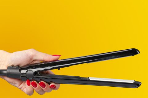 Eine Frau hält ein Ghd Glätteisen in der Hand.