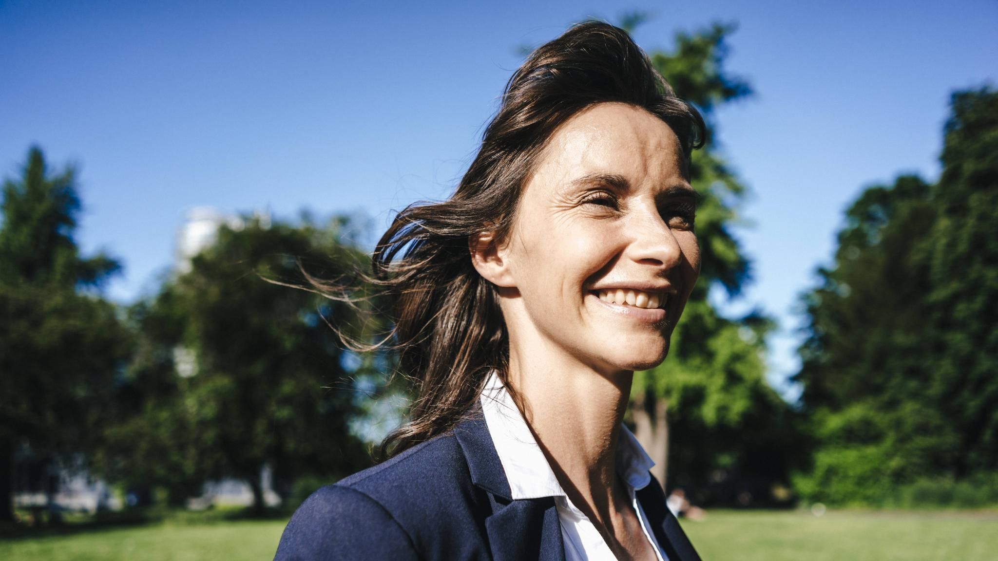 Eine Frau grinst breit (Symbolbild ungestresst bei der Arbeit)