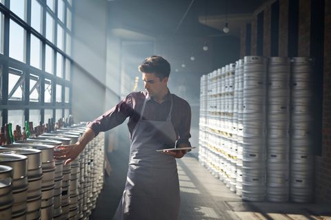 Ein junger Mann kontrolliert Fässer in einer Halle