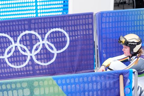 Emma Aicher sitzt nach ihrem Aus im Super-G frustriert im Zielbereich von Cortina d'Ampezzo. Foto: Michael Kappeler/dpa