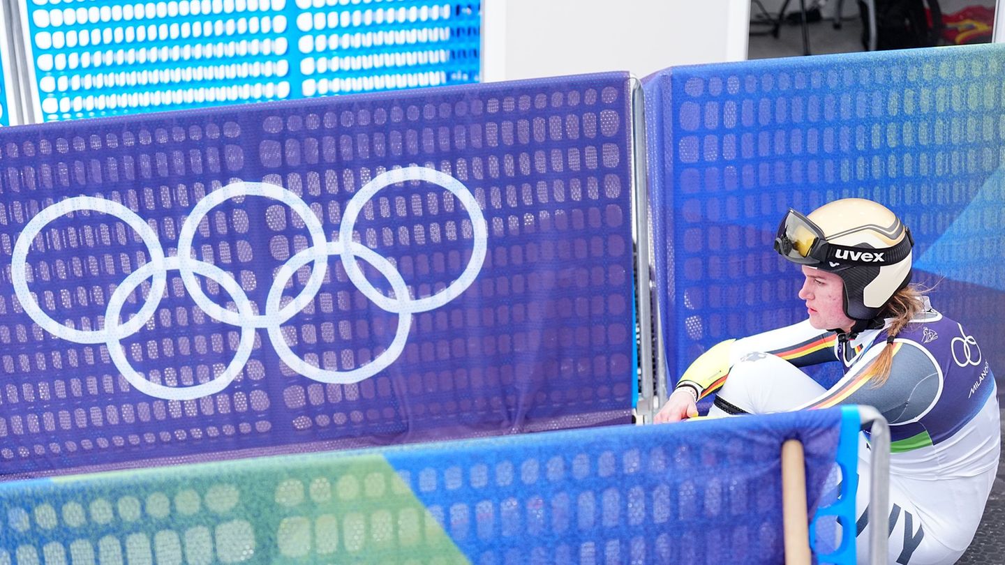 Emma Aicher sitzt nach ihrem Aus im Super-G frustriert im Zielbereich von Cortina d'Ampezzo. Foto: Michael Kappeler/dpa