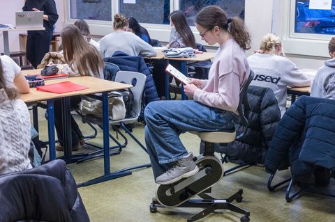 Deutschlektüre mit Bewegung: Eine Schülerin tritt mit den Füßen in die Pedale und liest gleichzeitig. Foto: Helmut Fricke/dpa
