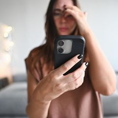 Eine junge Frau schaut auf das Smartphone. Nutzt sie Whatsapp?