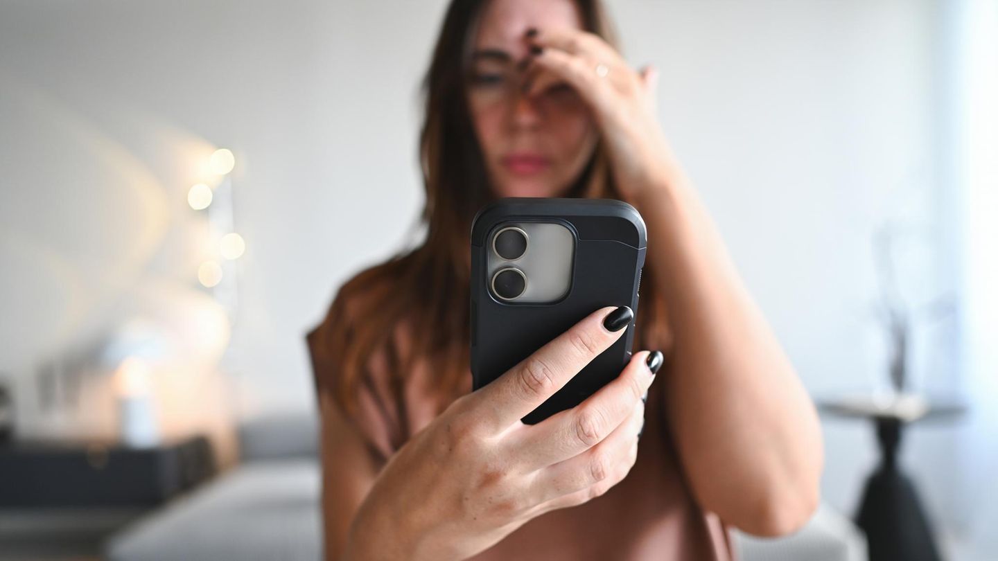 Eine junge Frau schaut auf das Smartphone. Nutzt sie Whatsapp?