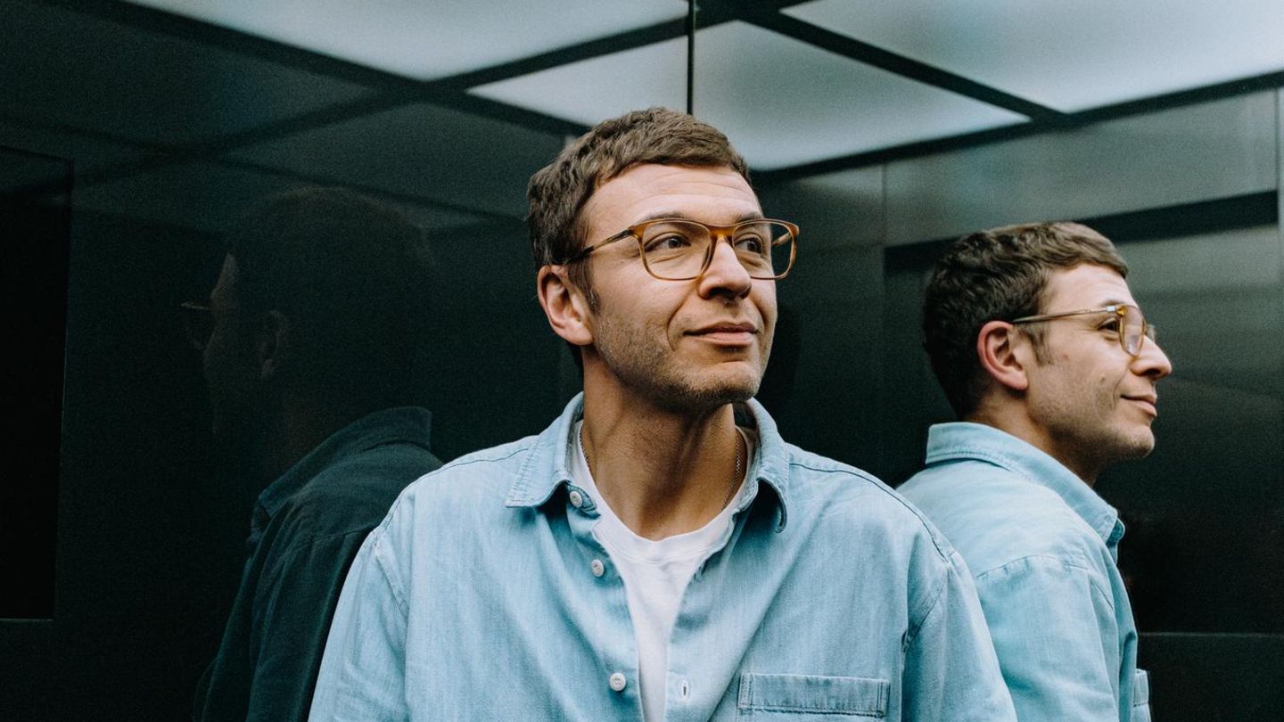 Boris Ewenstein fährt im Fahrstuhl des Otto-Hauptgebäudes in Hamburg, sein Gesicht wird von den Fahrstuhlwänden reflektiert