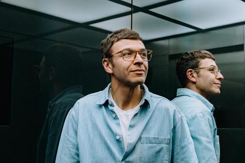 Boris Ewenstein fährt im Fahrstuhl des Otto-Hauptgebäudes in Hamburg, sein Gesicht wird von den Fahrstuhlwänden reflektiert