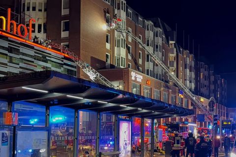 Einsatzkräfte der Feuerwehr arbeiten auf Drehleitern an einem Wohnhaus neben dem Einkaufszentrum Sophienhof in Kiel