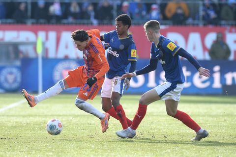 Die Kieler Marko Ivezic und Andu Kelati bedrängen den Schalker Soufiane El-Faouzi. Foto: Daniel Bockwoldt/dpa