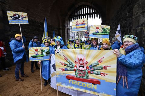 Der ukrainische Hilfsverein Blau-Gelbes-Kreuz hält Plakate mit Putin-Motiven hoch. Das ist als Zeichen der Solidarität mit Wagen