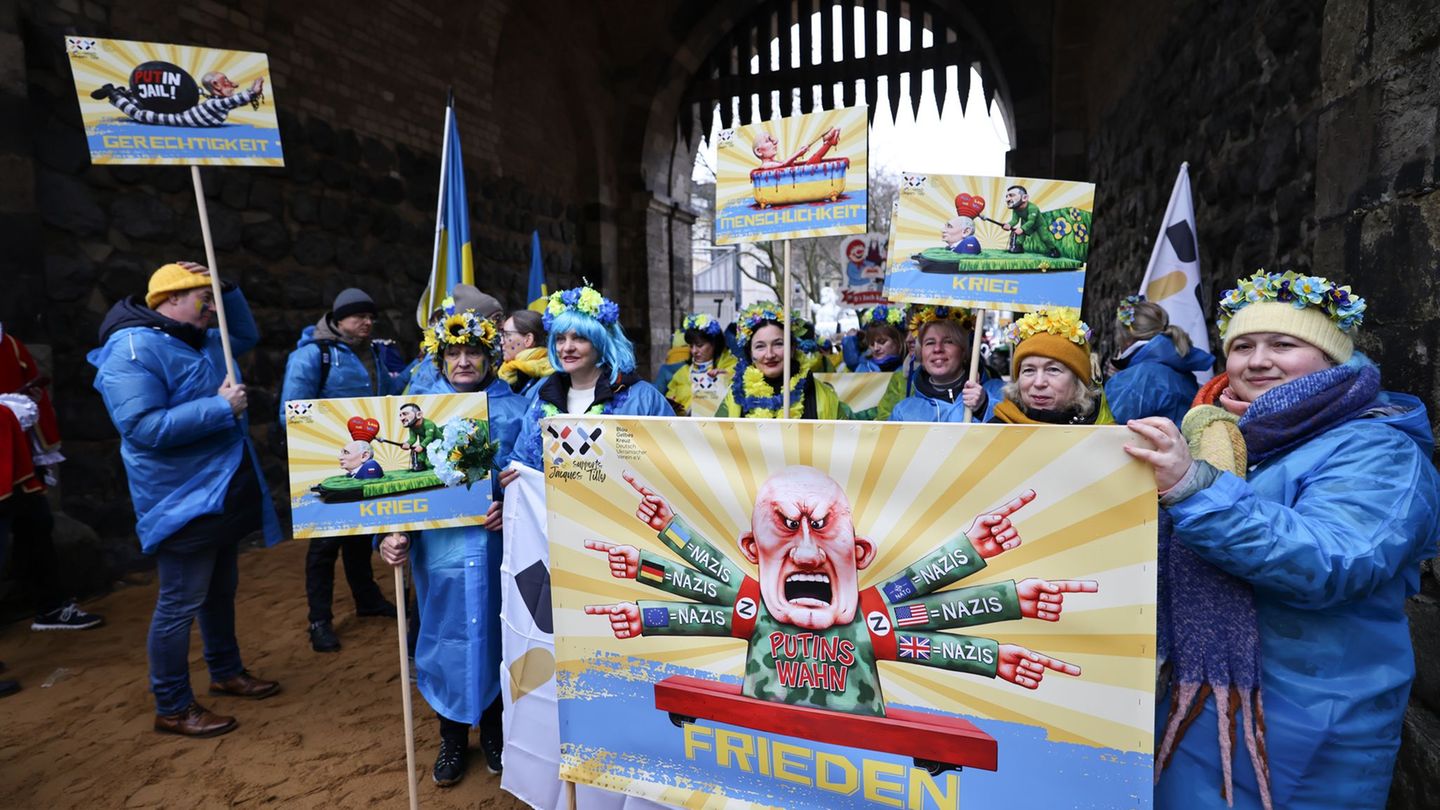 Der ukrainische Hilfsverein Blau-Gelbes-Kreuz hält Plakate mit Putin-Motiven hoch. Das ist als Zeichen der Solidarität mit Wagen