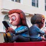 „Kindheit … heute“: Hypnotisiert vom Smartphone starren zwei Kinder auf die Bildschirme in ihren Händen. Aktuell läuft weltweit die Debatte darüber, Handynutzung für Kinder per Gesetz einzuschränken: Ein Social-Media-Verbot für Jugendliche hat Australien etwa durchgesetzt.