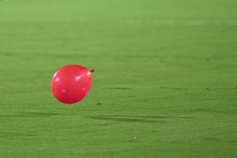 Roter Luftballon auf Rasen