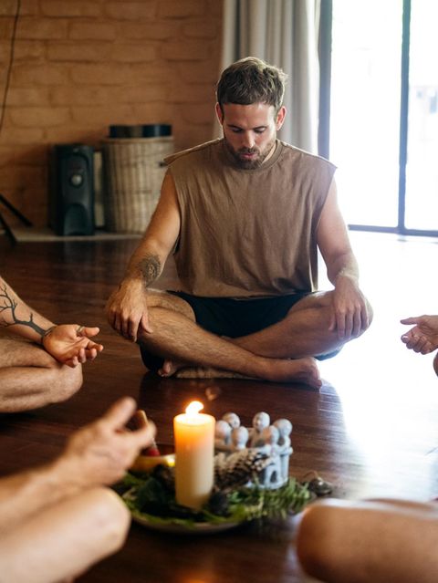 Mann sitzt mit anderen in einem Kreis und meditiert konzentriert (Symbolbild Buddhismus)