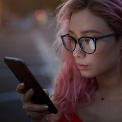 Eine junge Frau schaut aufs Smartphone. Nutzt sie Whatsapp?