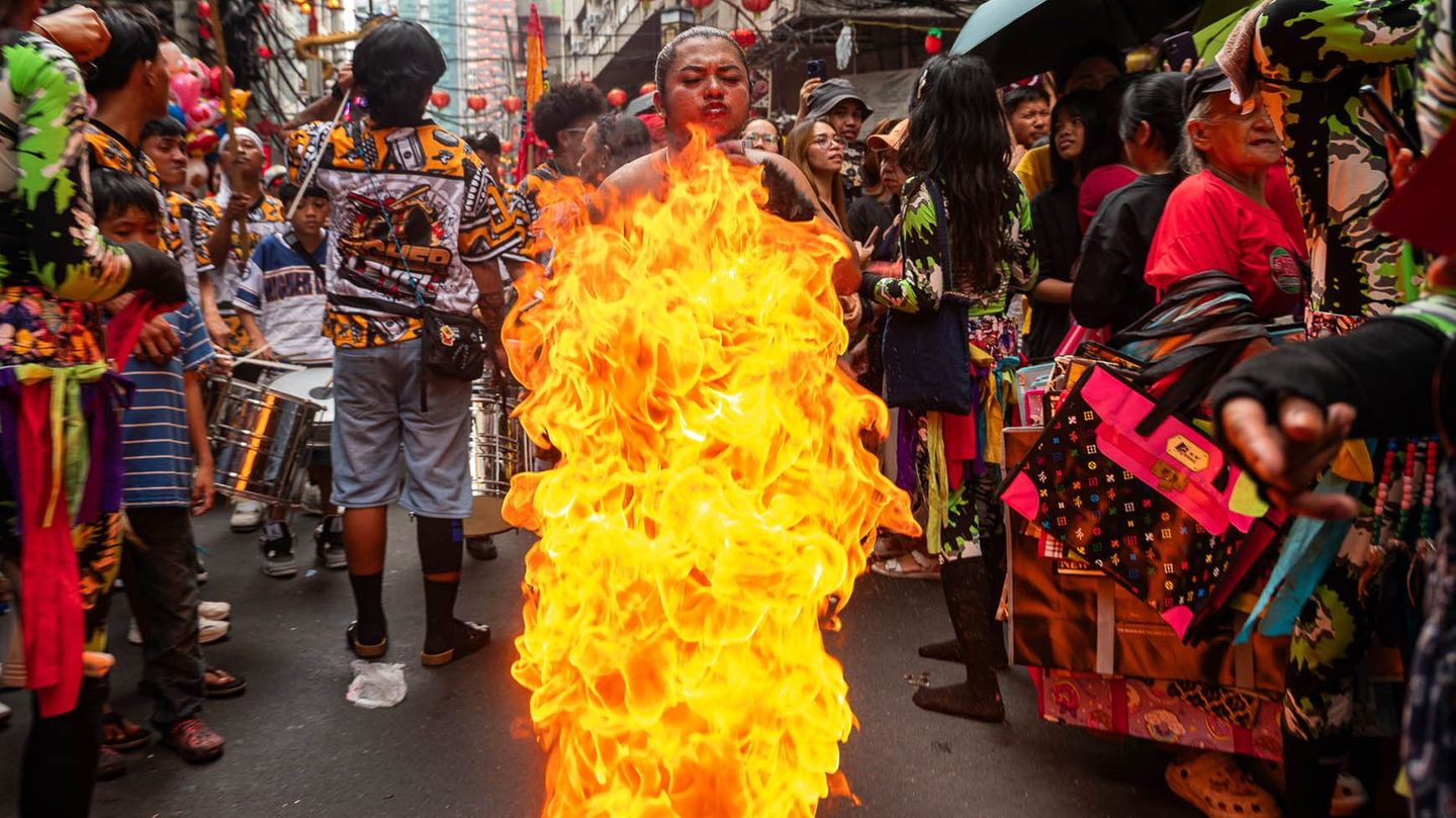 Ein Feuerspucker spuckt Flammen für die Zuschauer aus