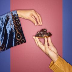 Ramadan-Symbolbild: Hände greifen nach einer Schale mit Datteln