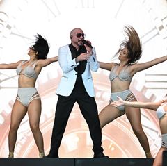 Sänger Pitbull singt auf der Bühne zwischen mehreren Tänzerinnen