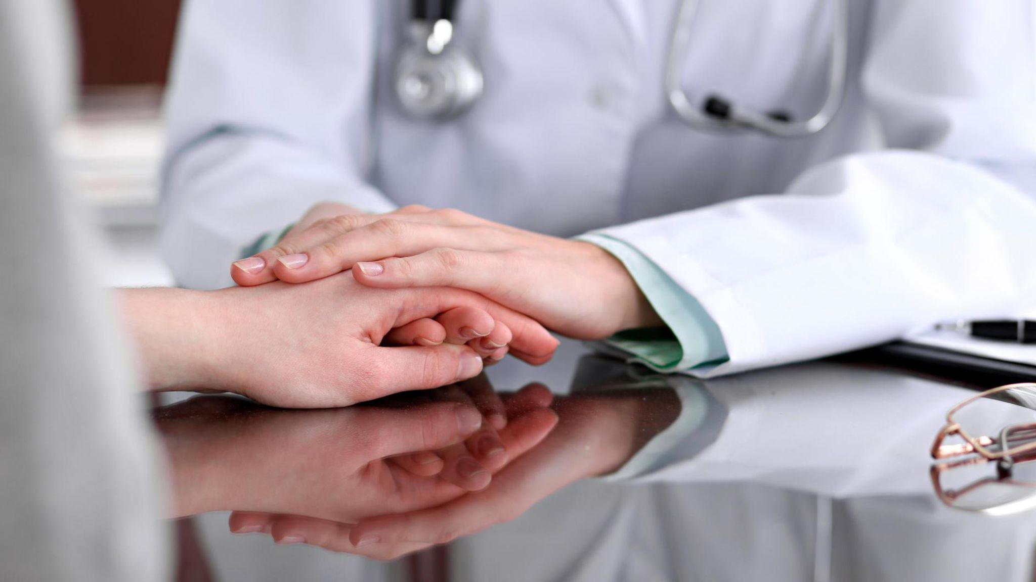 Vertrauen: eine Ärztin hält die Hand eines Patienten