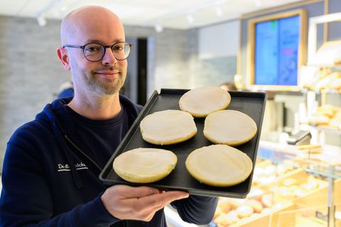 Jannik Harms, Geschäftsführer der De Heidbäcker GmbH, hält ein Blech "Grönländer" in der Hand. Foto: Philipp Schulze/dpa