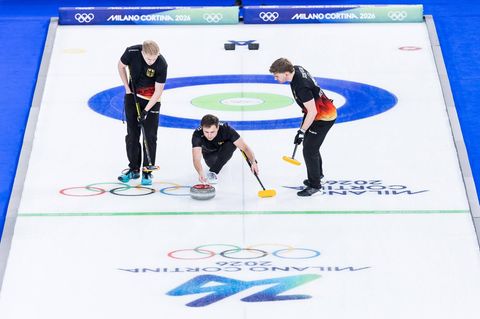Olympia drei Curlingspieler bei der Steinabgabe
