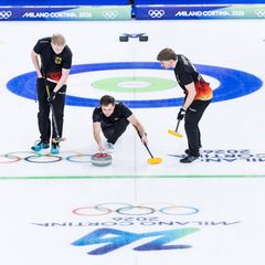 Olympia drei Curlingspieler bei der Steinabgabe