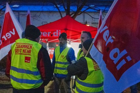 Streikende halten Fahnen der Gewerkschaft Verdi und sind mit Warnwesten gekleidet. Foto: Stefan Puchner/dpa