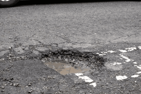 Schlaglöcher: Ein Auto fährt über ein Schlagloch