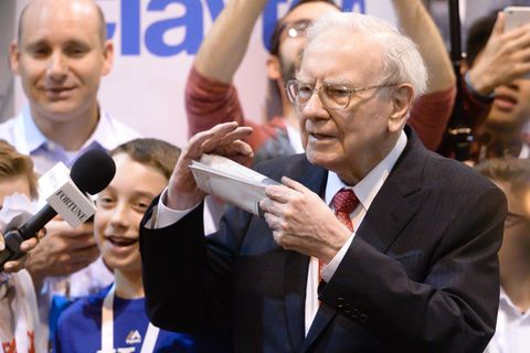Warren Buffett mit Zeitung in der Hand, umgeben von Repotern