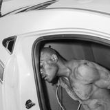 Ein Mann sitzt in einem Polizeiauto, seine Augen sind geschlossen und seine Hände gefesselt