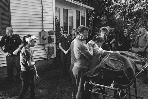 Eine eindrucksvolle Fotografie, wo eine Familie und Beamte um eine Trage mit einem Leichensack stehen