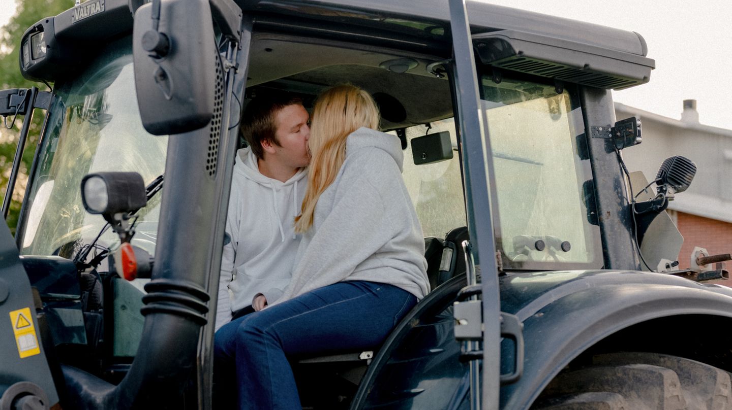 Ein junges Paar küsst sich auf einem Traktor