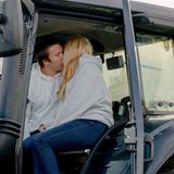 Ein junges Paar küsst sich auf einem Traktor